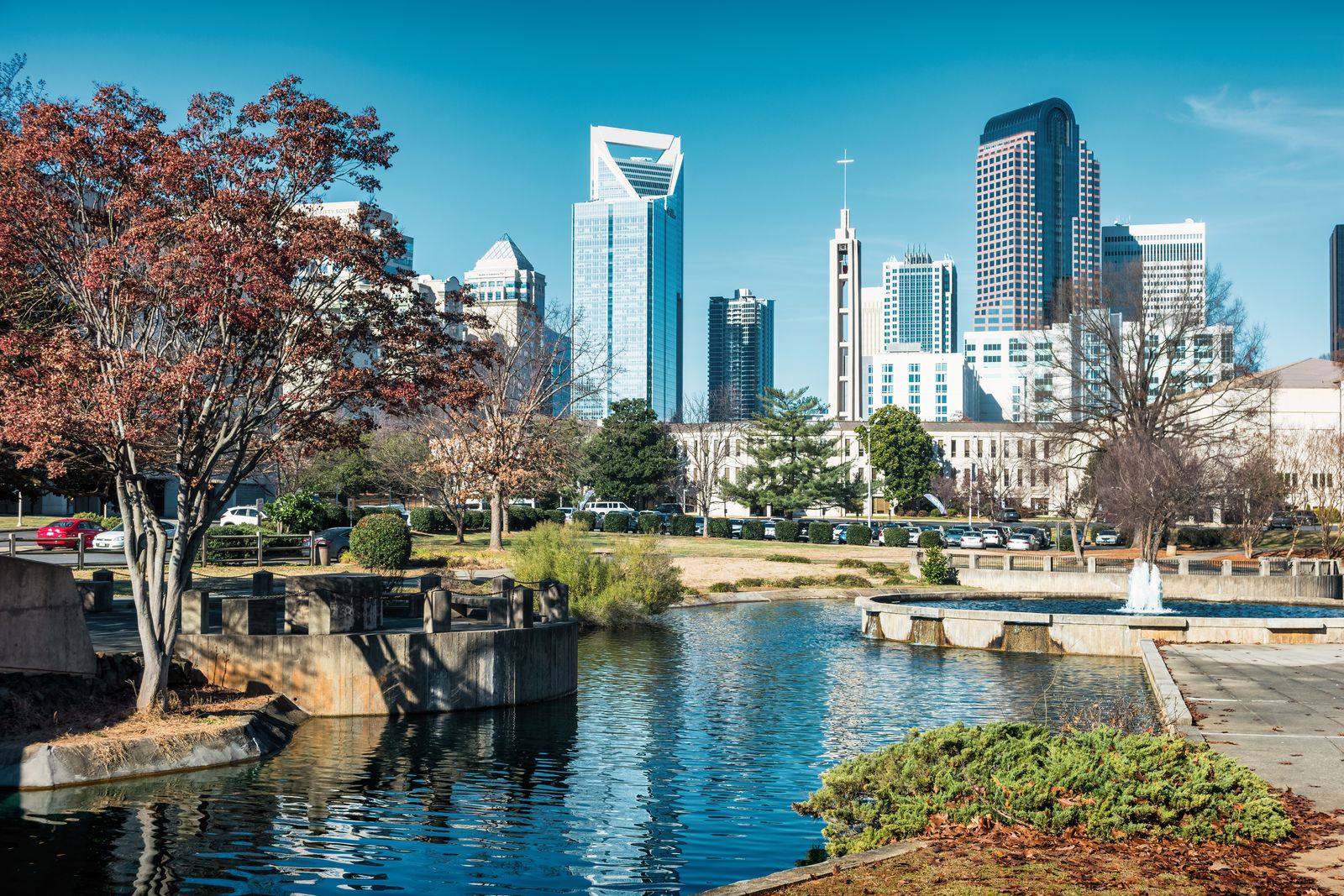 Uptown Charlotte skyline above a city park pond on a sunny day