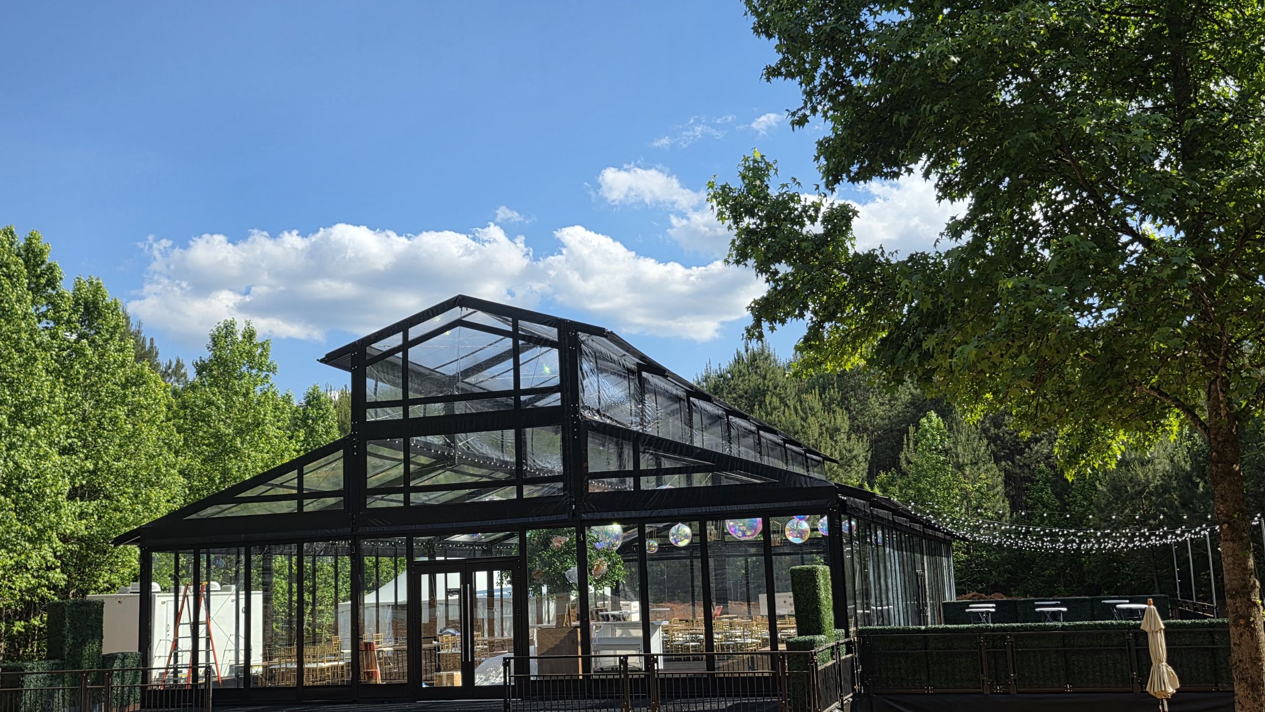 Black-framed glass event structure under the trees on a sunny day